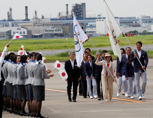 © Reuters. Tokyo governor Yuriko Koike and Japan's Olympic team's sub-captain Keisuke Ushiro wave the Olympic flag and JOC flag during a ceremony to mark the arrival of the Olympic flag at Haneda airport  in Tokyo
