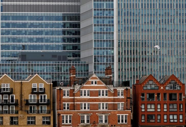 © Reuters. Apartment buildings are backdropped by skyscrapers of banks at Canary Wharf in London