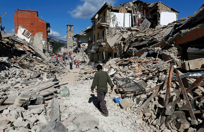 © Reuters. Un hombre camina entre los escombros de las viviendas tras un terremoto 6,2. que sacudió el centro de Italia, en Pescara del Tronto.