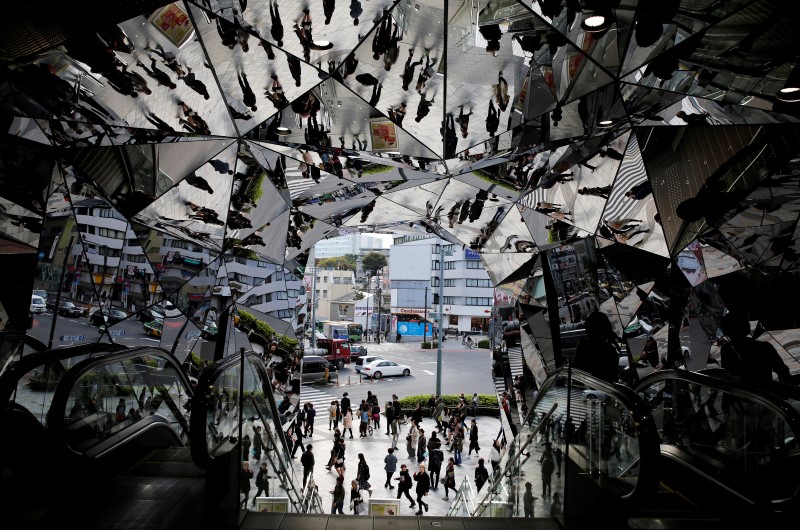 © Reuters. People are reflected in mirrors at an entrance to a department store in Tokyo