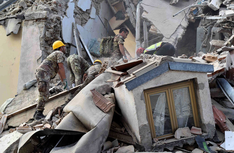 © Reuters. Rescuers work at a collapsed building following an earthquake in Amatrice