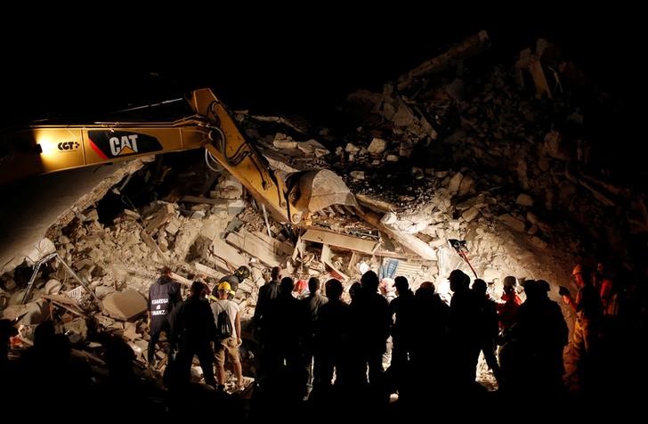 © Reuters. Soccorritori al lavoro nella notte intorno a una casa crollata per il terremoto a Pescara del Tronto.