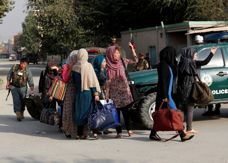 © Reuters. Students walk toward a police vehicle after they were rescued from the site of an attack at the American University of Afghanistan in Kabul