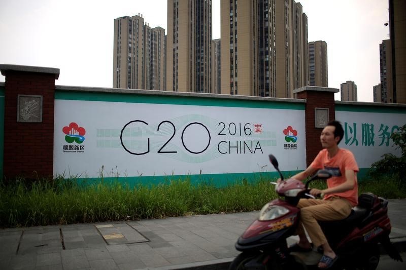 © Reuters. A man rides an electronic bike past a billboard for the upcoming G20 summit in Hangzhou