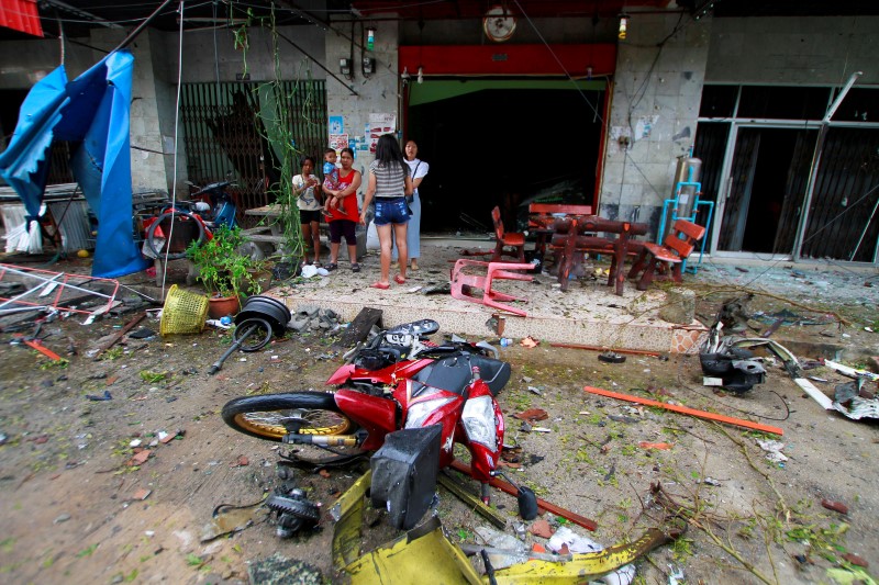 © Reuters. People stand at the scene after a blast outside a hotel in the southern province of Pattani