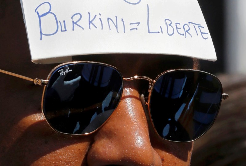 © Reuters. A man wears a placard with a message outside the Conseil d'Etat after France's highest administrative court suspended a ban on full-body burkini swimsuits in Paris