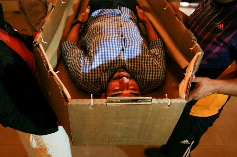 © Reuters. Elio Angulo lies inside a cardboard coffin as he introduces his product to potential customers at a mortuary in Valencia