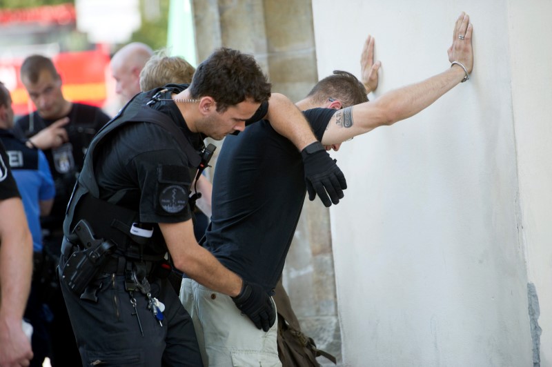 © Reuters. A German police officer searches the pockets of a member of far right Identitarian movement  after the activists staged a demonstration on top of the Brandenburg Gate in Berlin