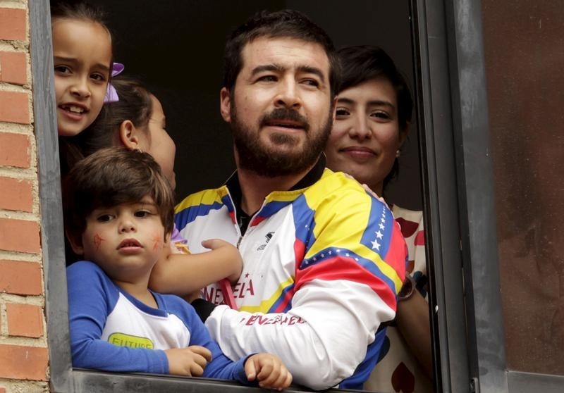 © Reuters. Former mayor Daniel Ceballos looks out from a window next to his wife Patricia Ceballos, mayor of San Cristobal and their children at their house in Caracas
