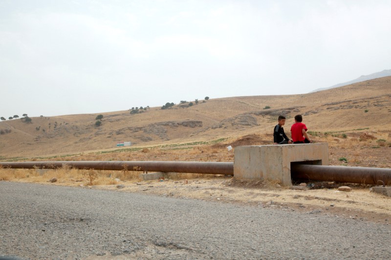 © Reuters. Boys sit on the Iraqi-Turkish pipeline in Zakho district of the Dohuk Governorate of the Iraqi Kurdistan province