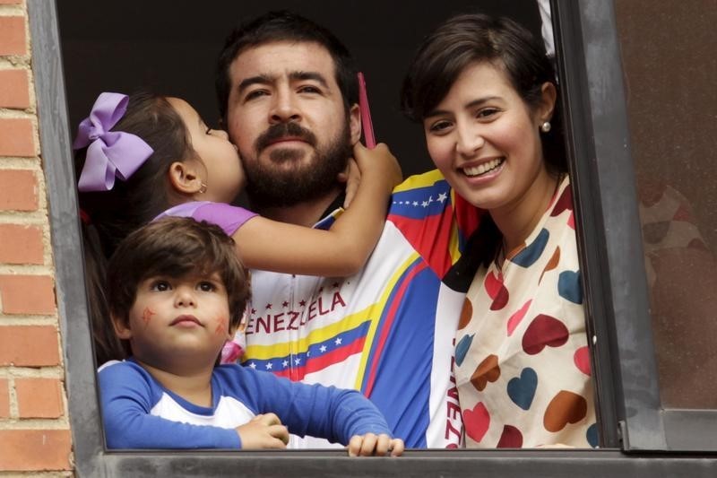 © Reuters. Former mayor Daniel Ceballos (C), looks out from a window next to his wife Patricia Ceballos, mayor of San Cristobal and their children at their house in Caracas