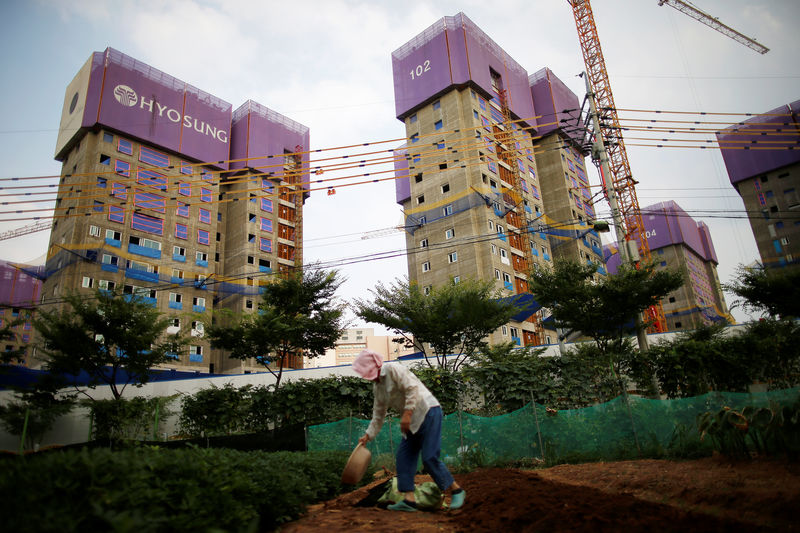 © Reuters. A woman works on her kitchen garden in front of an apartment complex which is currently under construction in Yongin