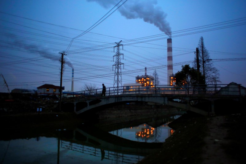 © Reuters. A man walks over a bridge as smoke rises from chimneys of a thermal power plant in Shanghai