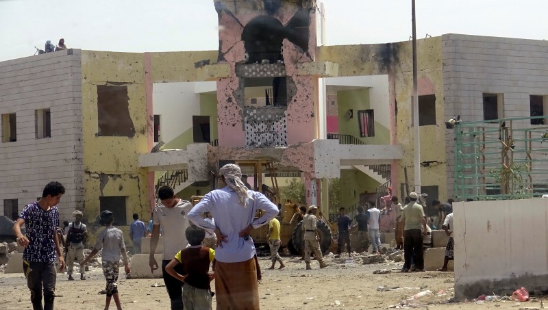 © Reuters. People gather at the scene following an attack by a suicide bomber who drove a car laden with explosives into a compound run by local militias in the port city of Aden, Yemen