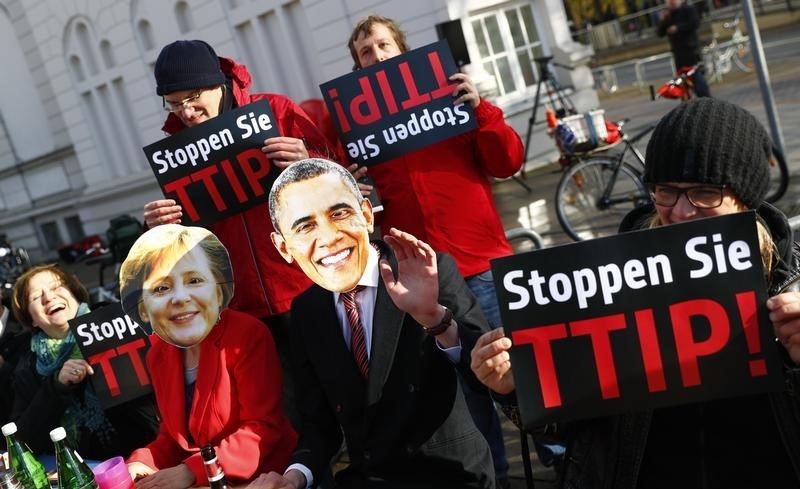 © Reuters. Protesters wear masks of U.S. President Obama and German Chancellor Merkel as they demonstrate against TTIP free trade agreement before the opening ceremony of the Hannover Messe in Hanover