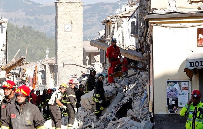 © Reuters. Firefighters and rescuers work following an earthquake in Amatrice