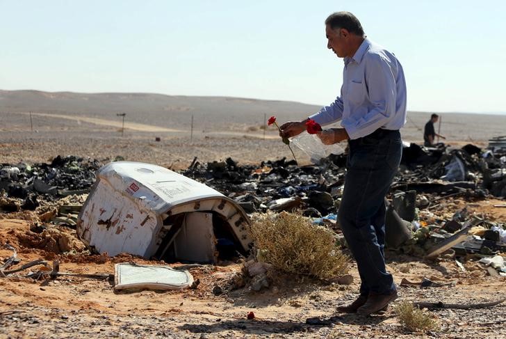 © Reuters. An Egyptian man puts flowers near debris at the crash site of a Russian airliner in al-Hasanah area at El Arish city, north Egypt