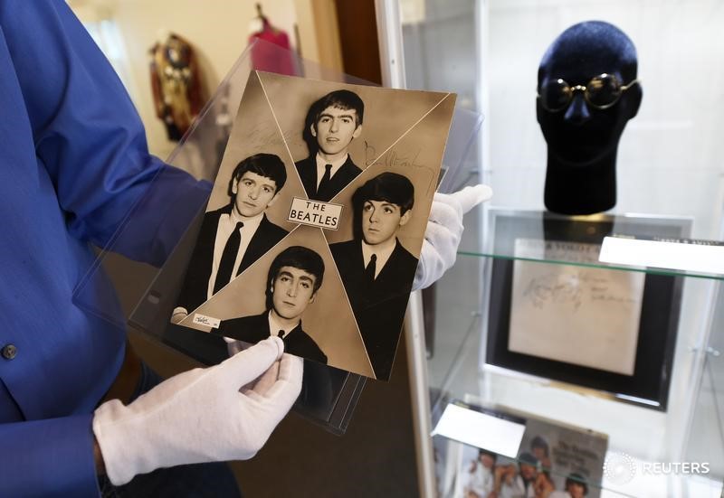 © Reuters. Martin Nolan, director ejecutivo de la casa de subasta Julien, muestra una fotografía publicitaria autografiada por los Beatles, junto a los lentes usados por John Lennon, subastados en el evento de "Icons & Idols: Rock n Roll" en Beverly H