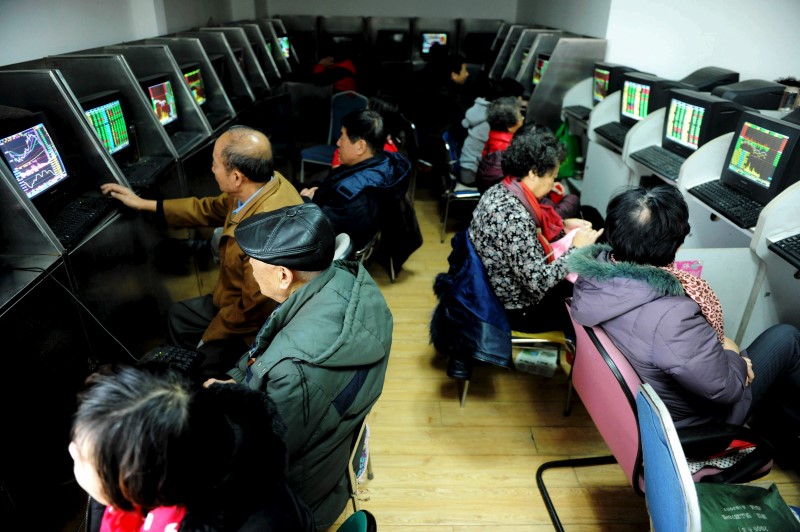 © Reuters. Investors look at computer screens showing stock information at brokerage house in Qingdao