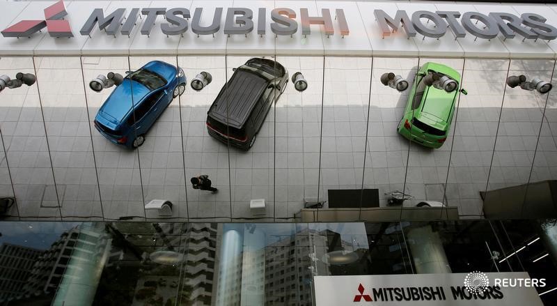 © Reuters. Mitsubishi Motors Corp's vehicles and a passer-by reflected on an external wall at the company headquarters in Tokyo