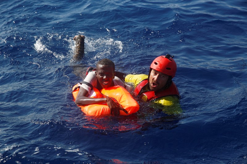 © Reuters. A member of the Spanish NGO Proactiva rescues a Somali migrant that fell from an overcrowded dinghy, during a rescue operation off the Libyan coast in Mediterranean Sea