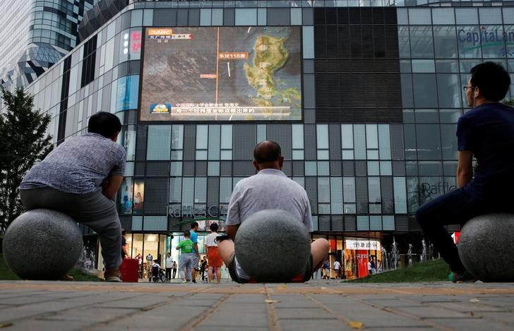 © Reuters. Pessoas assistindo telejornal em telão em shopping em Pequim