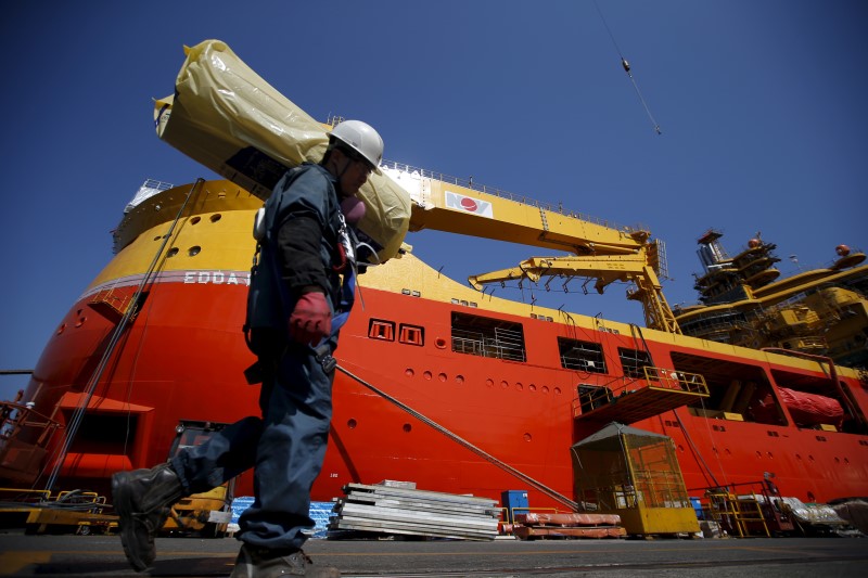 © Reuters. Worker carries construction materials as he walks past a ship which is currently under construction at Hyundai Heavy Industries' Shipyard in Ulsan, South Korea