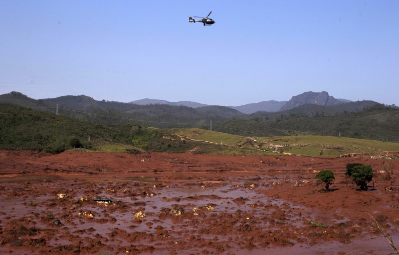 © Reuters. A helicopter flies over the Bento Rodrigues district, covered with mud after a dam owned by Vale SA and BHP Billiton Ltd burst in Mariana