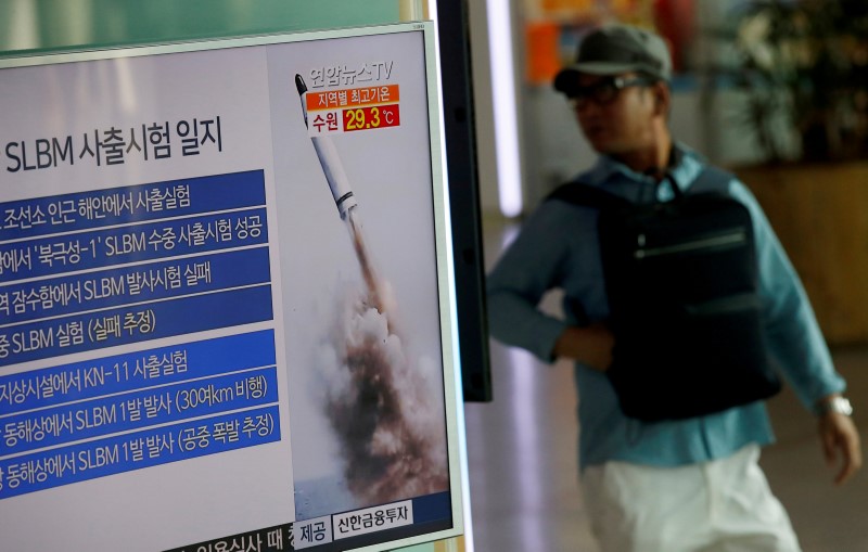 © Reuters. A passenger walks past TV screen broadcasting news report on North Korea's submarine-launched ballistic missile fired from North Korea's east coast port of Sinpo, at a railway station in Seoul