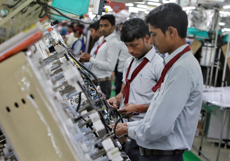 © Reuters. Employees of Motherson Sumi Systems Limited, work on a car wiring assembly line inside a factory in Noida