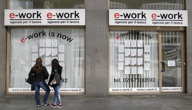 © Reuters. People check job offers outside a recruitment agency in downtown Milan