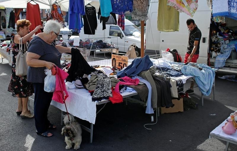 © Reuters. Women check clothes in a street market in Rome