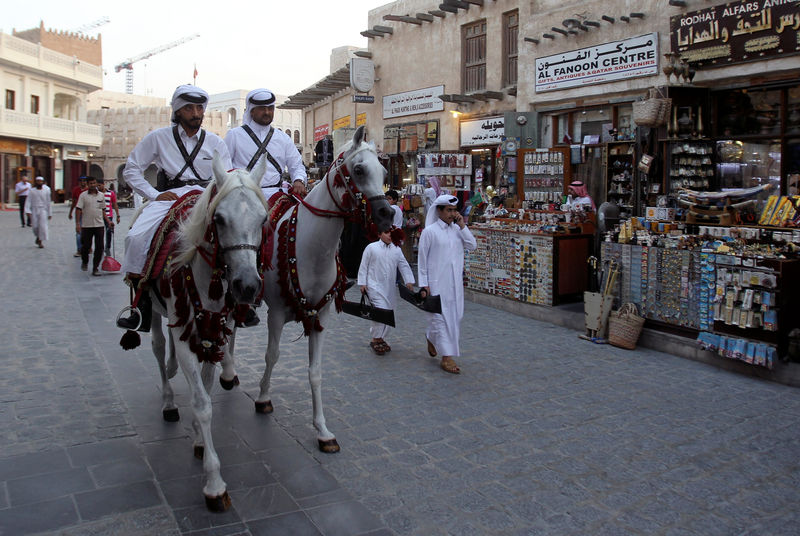 © Reuters. Qatari men ride horses as they parade at Souq Waqif market in Doha