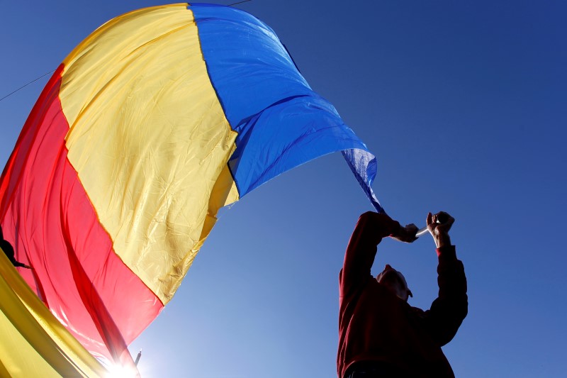 © Reuters. Man waves a Romanian national flag during a march in downtown Bucharest