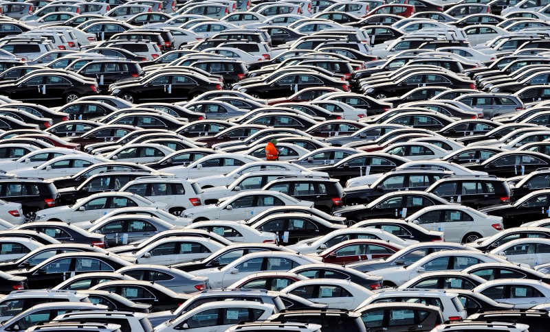 © Reuters. A worker walks along rolls of Mercedes cars at a shipping terminal in the harbor of the town of Bremerhaven