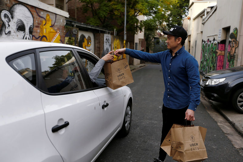 © Reuters. An Uber driver takes delivery of bags of donuts destined for a customer  via Uber Eats in Sydney