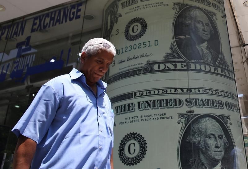 © Reuters. A man walks past a currency exchange bureau advertisement showing images of the U.S dollar and other currencies in Cairo