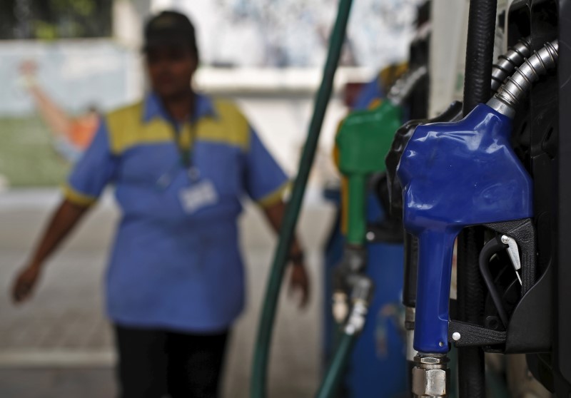 © Reuters. An employee stands next to a fuel pump at a fuel station in New Delhi