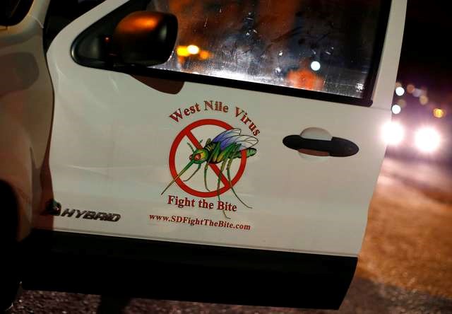 © Reuters. A vector control team vehicle displays a sign warning of West Nile Virus before the early morning spraying of a neighborhood
