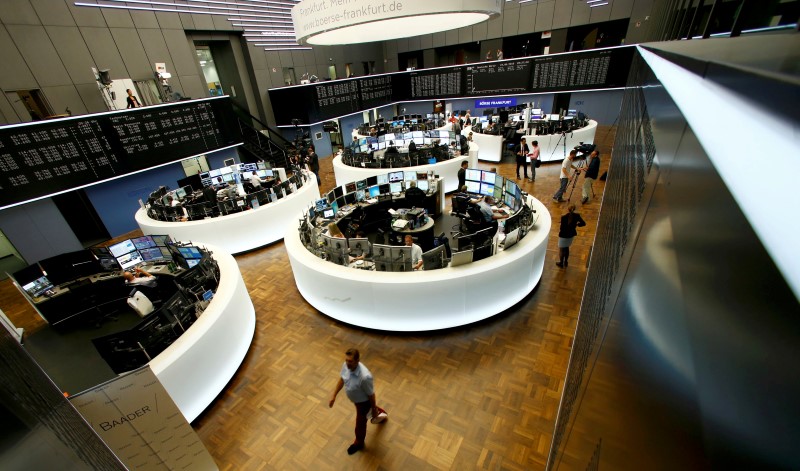 © Reuters. Traders work at their desks in front of the German share price index, DAX board, at the stock exchange in Frankfurt