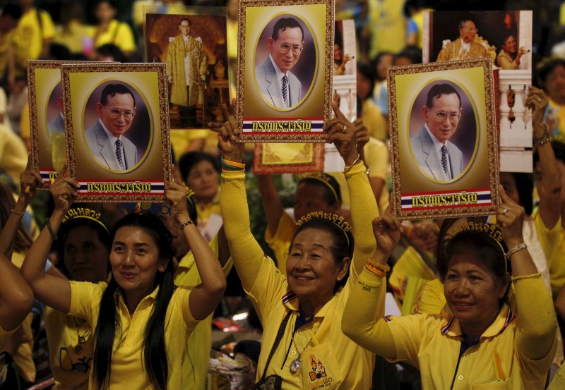 © Reuters. Well-wishers hold portraits of Thailand's King Bhumibol Adulyadej at Siriraj hospital, where a group has gathered to mark his 88th birthday, in Bangkok, Thailand