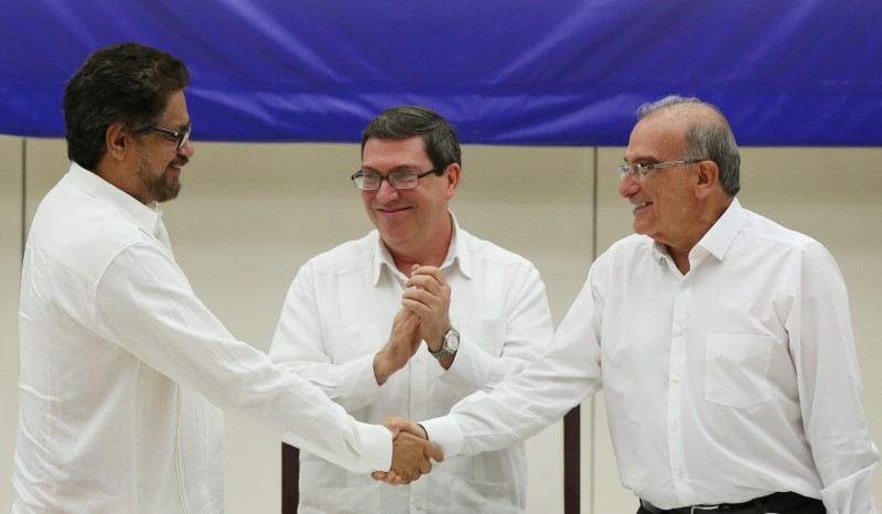 © Reuters. Colombia's FARC lead negotiator Ivan Marquez and Colombia's lead government negotiator Humberto de la Calle shake hands while Cuba's Foreign Minister Bruno Rodriguez looks on, after signing a final peace deal in Havana, Cuba