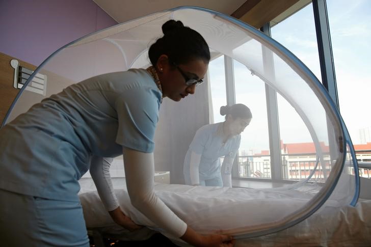 © Reuters. Enfermeras colocan un mosquitero en una cama de hospital, parte de las medidas preventivas que se usan para tratar a pacientes infectados con el virus de Zika, en Singapur