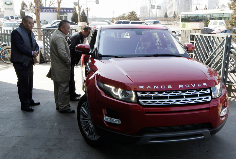 © Reuters. Customers look at a Range Rover Evoque car outside a dealership in Beijing