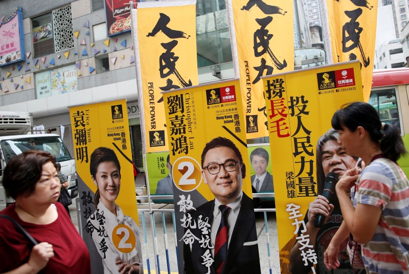 © Reuters. People walk past banners of Erica Yuen, Christopher Lau candidates from People Power and "Long Hair" Leung Kwok-hung, candidate from League of Social Democrats on election day for the Legislative Council in Hong Kong, China