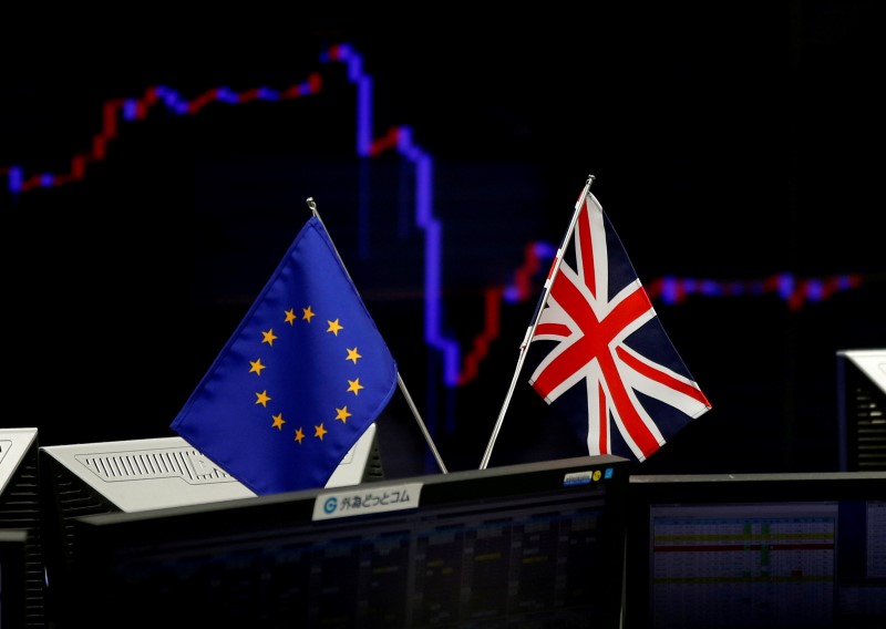 © Reuters. A British flag and an EU flag are seen in front of a monitor displaying a graph of the Japanese yen's exchange rate against the U.S. dollar at a foreign exchange trading company in Tokyo