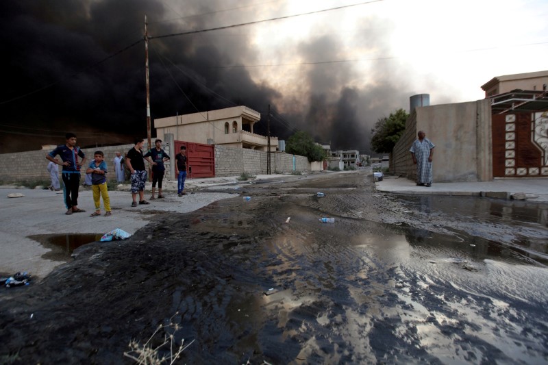 © Reuters. Residents look at oil spill from wells in Qayyara