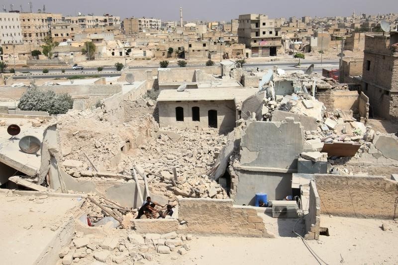 © Reuters. Civil defense members sit amid the rubble of damaged buildings after an airstrike in the rebel held Bab al-Nairab neighborhood of Aleppo