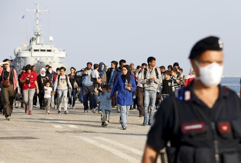 © Reuters. Syrian refugees are escorted by Carabinieri after disembarking from Belgian Navy vessel Godetia at the Augusta port, Italy