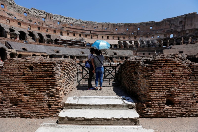 © Reuters. Tourists use an umbrella to protect themselves from the sun as they visit the Colosseum in Rome